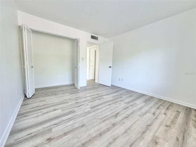 unfurnished bedroom with a closet, visible vents, baseboards, and light wood finished floors