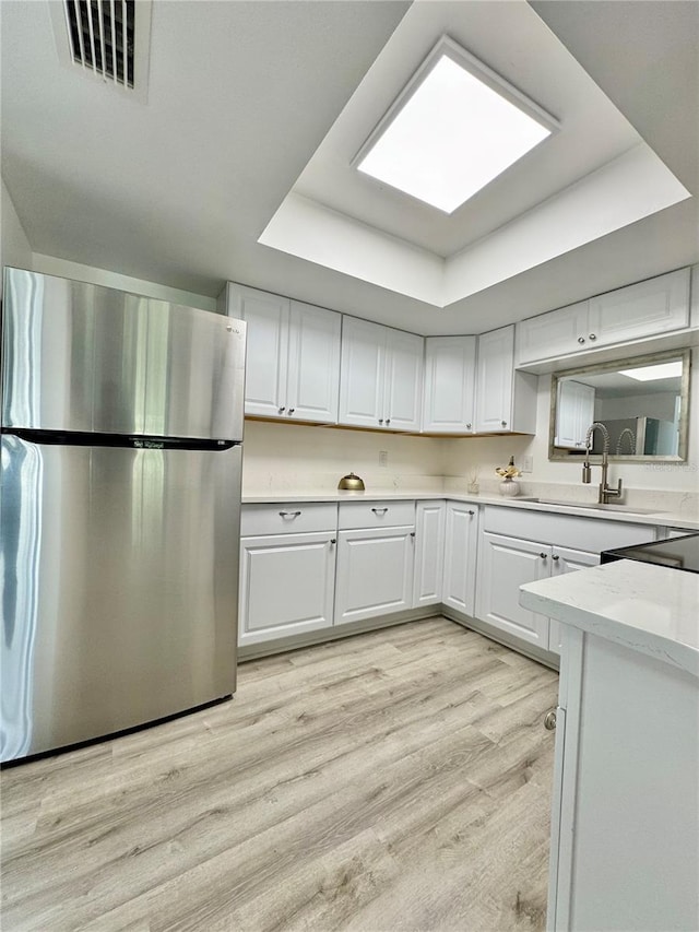 kitchen with a tray ceiling, light countertops, visible vents, freestanding refrigerator, and white cabinets