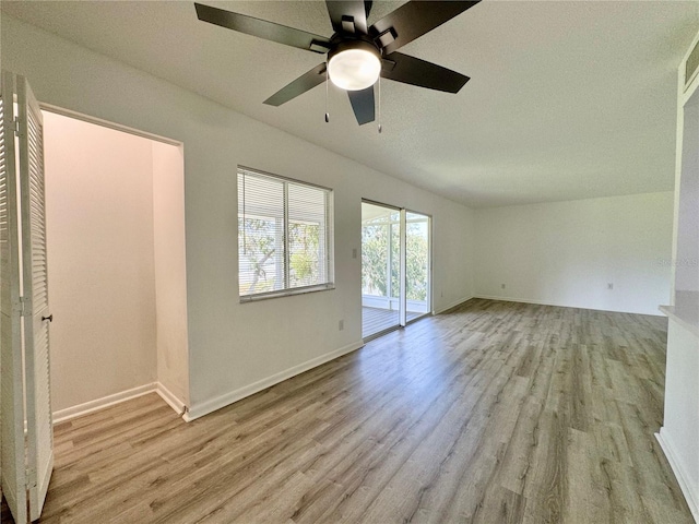 unfurnished room with light wood-style floors, vaulted ceiling, baseboards, and ceiling fan