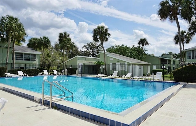 community pool with a patio area and fence