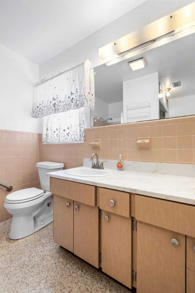 bathroom featuring vanity, toilet, and tile walls