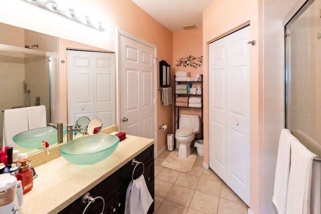 bathroom featuring tile patterned flooring, vanity, toilet, and walk in shower