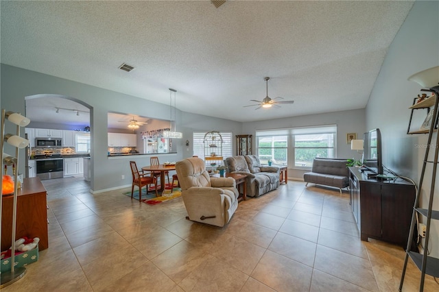 living room with ceiling fan, light tile patterned floors, vaulted ceiling, and a textured ceiling