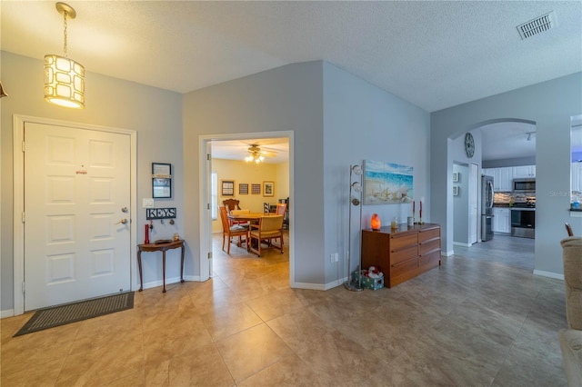 entrance foyer featuring lofted ceiling, a textured ceiling, and light tile patterned floors