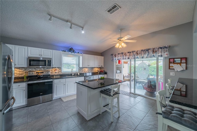 kitchen featuring white cabinetry, lofted ceiling, stainless steel appliances, and a center island