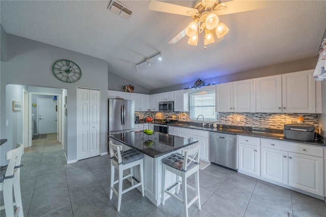 kitchen featuring white cabinetry, lofted ceiling, stainless steel appliances, and a kitchen breakfast bar