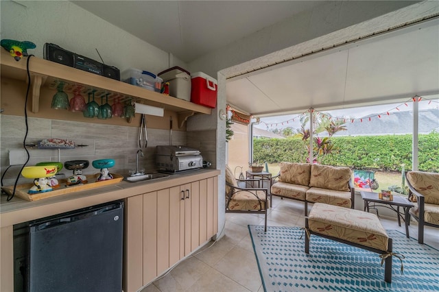 interior space with stainless steel refrigerator, light tile patterned floors, sink, and a wealth of natural light