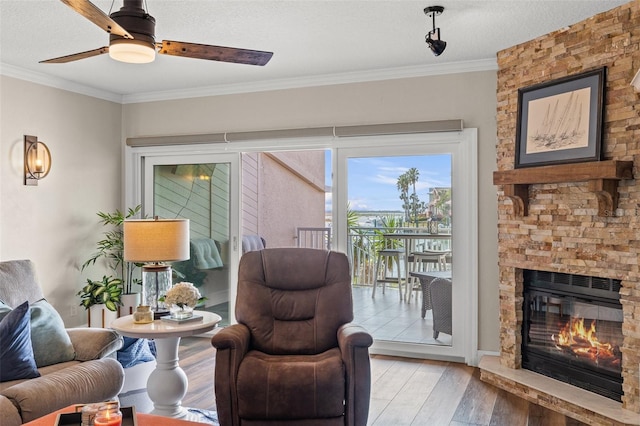 living area featuring hardwood / wood-style floors, crown molding, a fireplace, and a textured ceiling