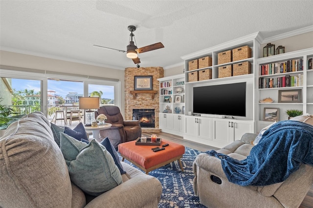 living room featuring crown molding, a textured ceiling, ceiling fan, a fireplace, and hardwood / wood-style floors