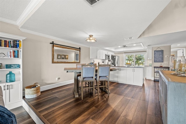 dining room with crown molding, dark hardwood / wood-style floors, and a tray ceiling