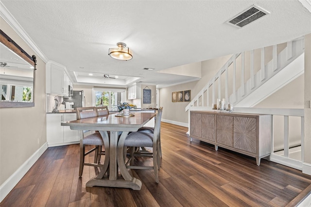 dining area featuring dark wood-type flooring, a healthy amount of sunlight, a tray ceiling, and a textured ceiling