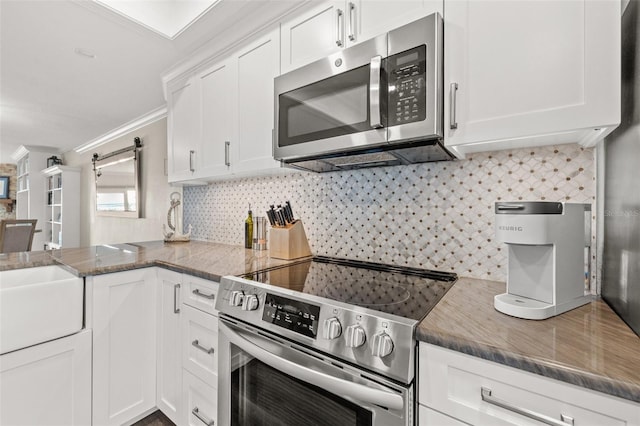 kitchen featuring stainless steel appliances, a barn door, and white cabinets