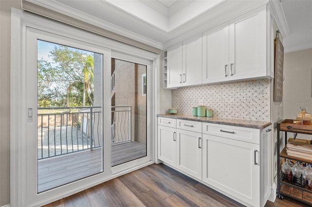 kitchen with crown molding, white cabinetry, light stone counters, tasteful backsplash, and dark hardwood / wood-style flooring