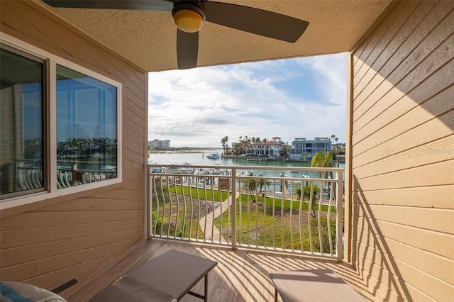 balcony featuring a water view and ceiling fan