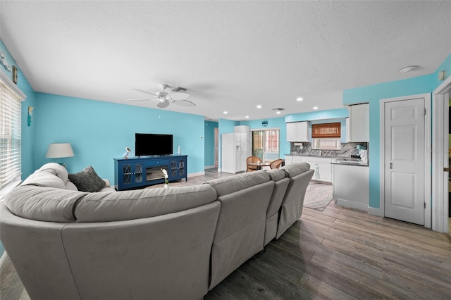 living room with dark wood-type flooring, a textured ceiling, and ceiling fan