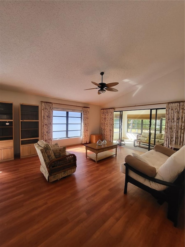 living room with dark wood-type flooring, ceiling fan, plenty of natural light, and a textured ceiling