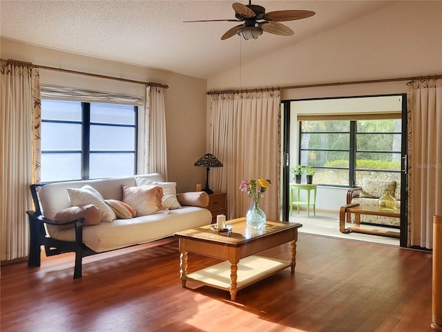 living room with lofted ceiling, hardwood / wood-style floors, a textured ceiling, and ceiling fan