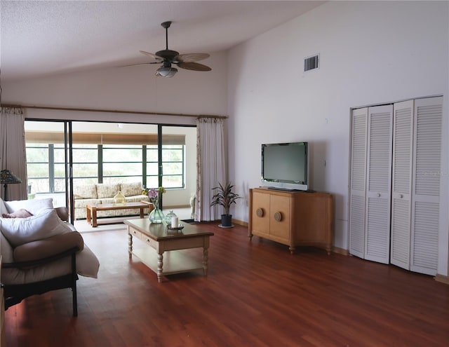 living room with ceiling fan, dark hardwood / wood-style flooring, and a towering ceiling