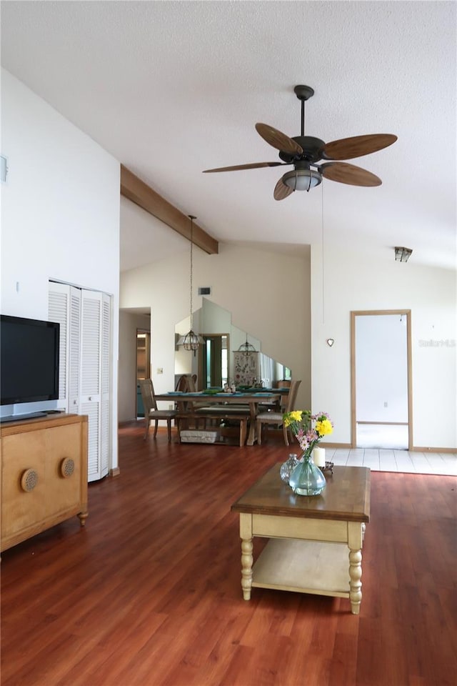 living room featuring hardwood / wood-style flooring, ceiling fan, a textured ceiling, and vaulted ceiling with beams