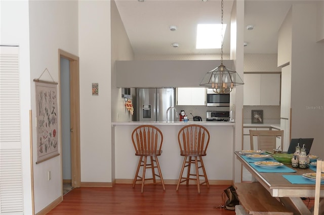 kitchen with pendant lighting, appliances with stainless steel finishes, dark hardwood / wood-style floors, white cabinets, and decorative backsplash