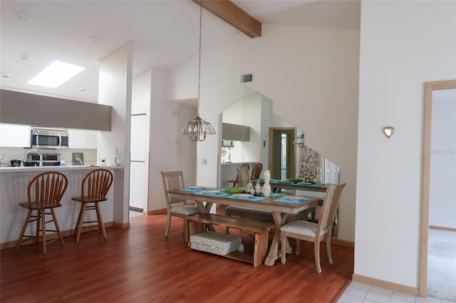 dining area featuring light hardwood / wood-style flooring, high vaulted ceiling, and beamed ceiling