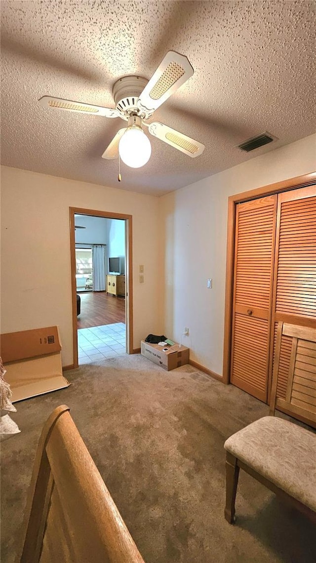 interior space featuring ceiling fan, carpet floors, and a textured ceiling