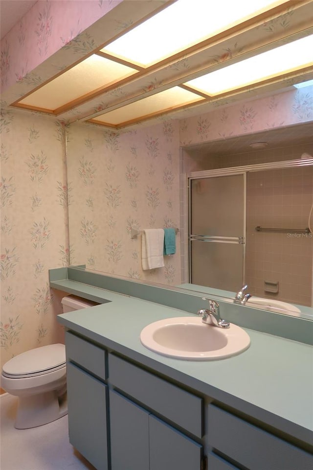 bathroom with vanity, a shower with door, and toilet