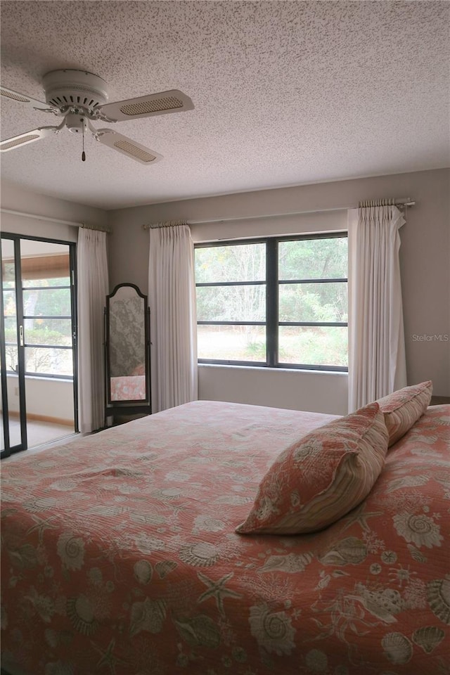 bedroom featuring multiple windows, access to exterior, a textured ceiling, and ceiling fan