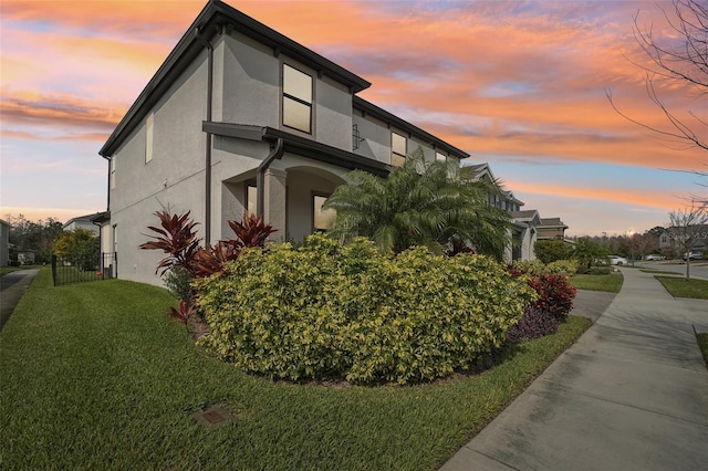 property exterior at dusk with a lawn