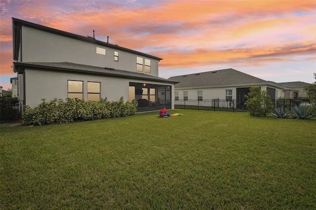 back house at dusk with a lawn