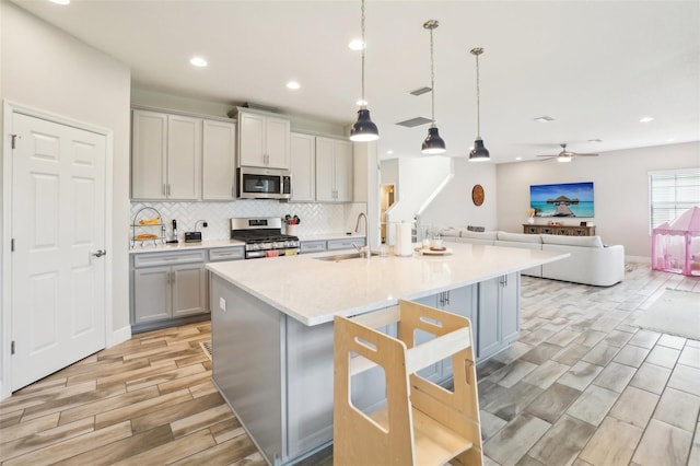 kitchen featuring pendant lighting, sink, a kitchen island with sink, and stainless steel appliances