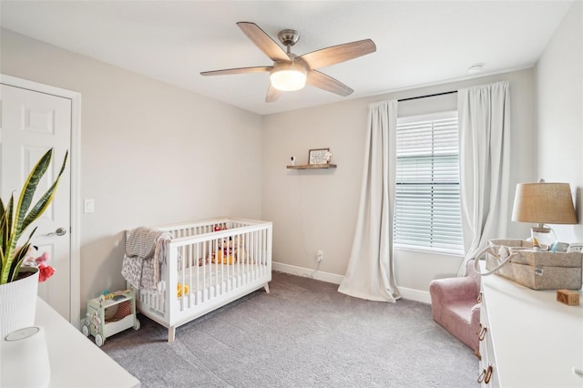 bedroom with light carpet, a crib, and ceiling fan