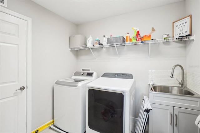 laundry area with sink, washing machine and dryer, and cabinets