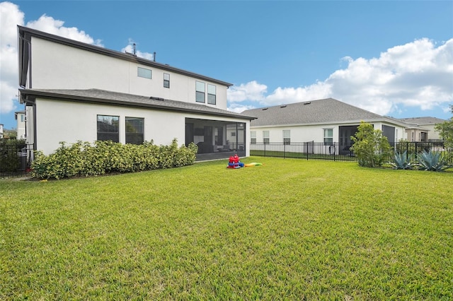 rear view of house with a sunroom and a lawn