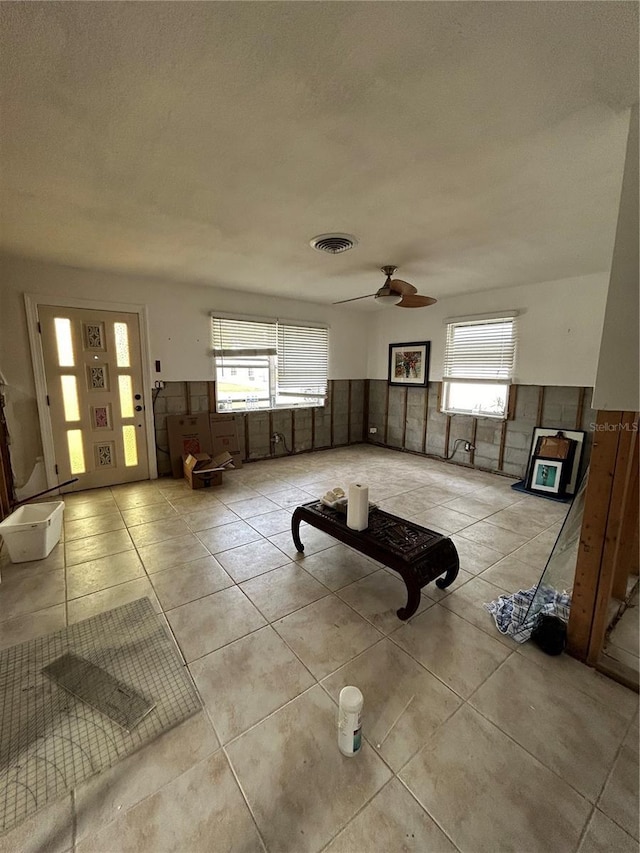 unfurnished living room featuring a ceiling fan, visible vents, and light tile patterned floors