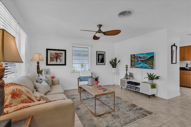 living room with a wealth of natural light, a ceiling fan, light tile patterned floors, and visible vents