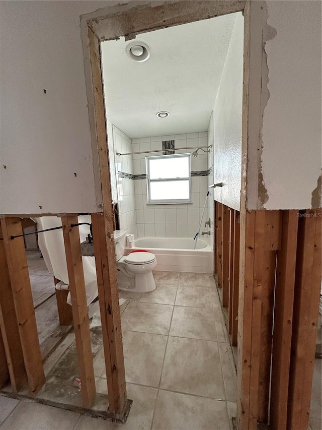 bathroom with tile patterned flooring, toilet, and bathing tub / shower combination