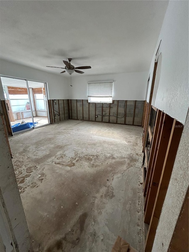 spare room with a ceiling fan and unfinished concrete flooring