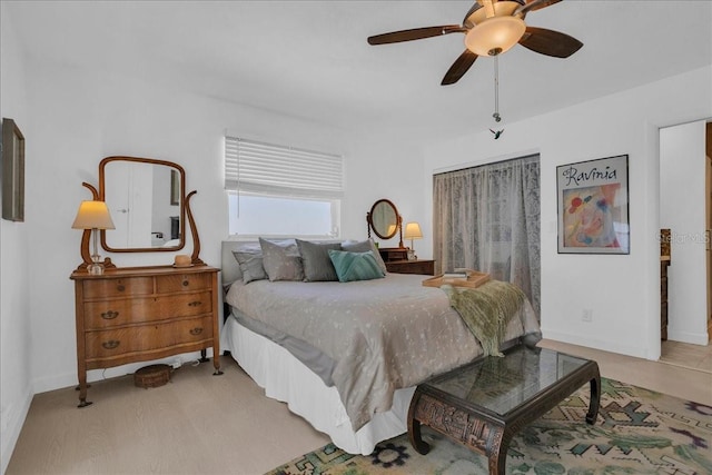 bedroom with light wood finished floors, a ceiling fan, and baseboards