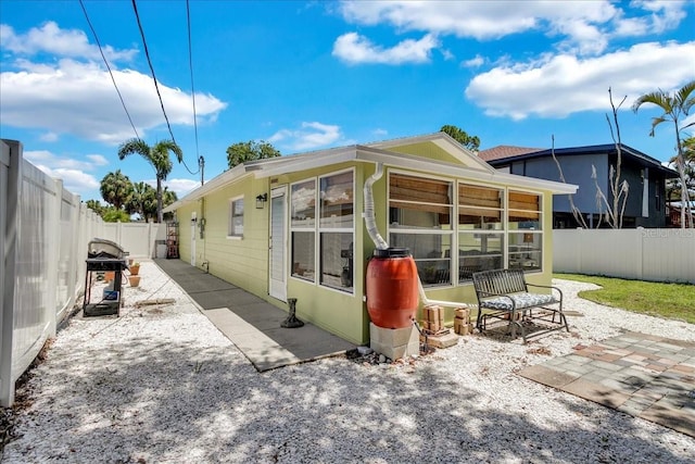 rear view of house with a patio area, a sunroom, and a fenced backyard