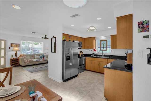 kitchen with plenty of natural light, dark countertops, stainless steel appliances, and a sink