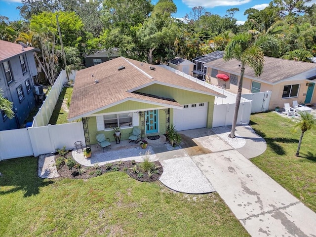 view of front of house with a front lawn, driveway, a shingled roof, a fenced backyard, and a garage