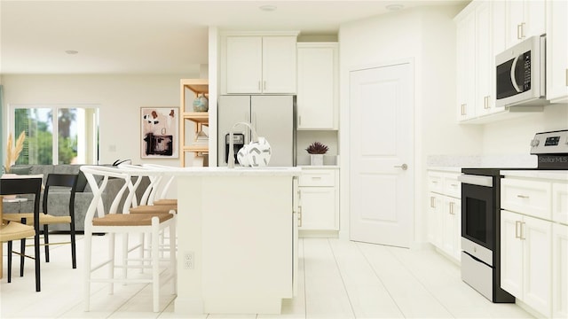 kitchen with white cabinetry, stainless steel appliances, a kitchen bar, and a center island