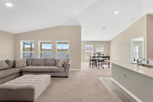 living room with lofted ceiling, sink, and light carpet