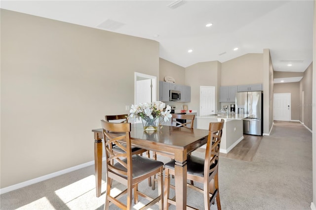 carpeted dining space featuring high vaulted ceiling