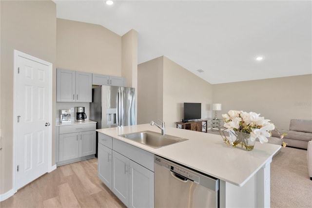 kitchen featuring lofted ceiling, sink, appliances with stainless steel finishes, gray cabinets, and a kitchen island with sink