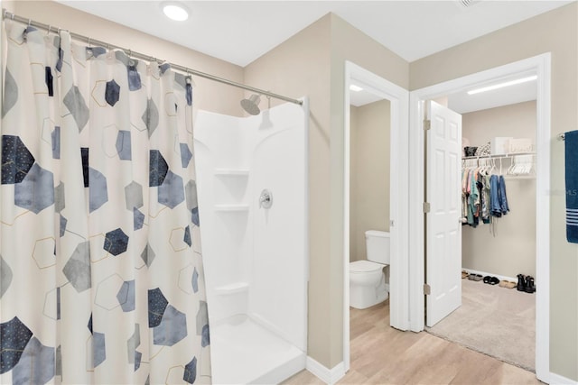 bathroom featuring wood-type flooring, toilet, and a shower with curtain