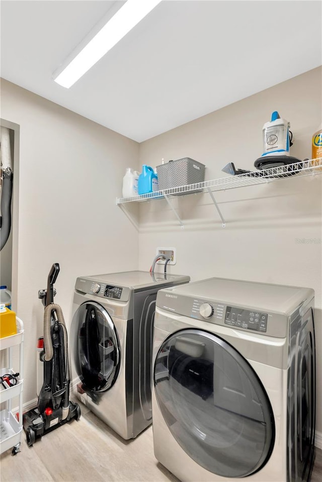 laundry area with washing machine and dryer and light hardwood / wood-style floors