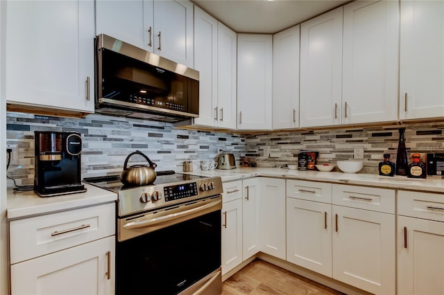 kitchen featuring tasteful backsplash, white cabinetry, appliances with stainless steel finishes, and light hardwood / wood-style flooring