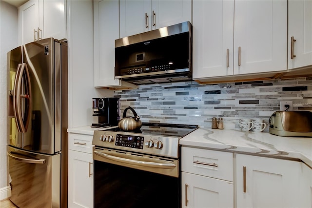 kitchen with light stone countertops, decorative backsplash, stainless steel appliances, and white cabinets